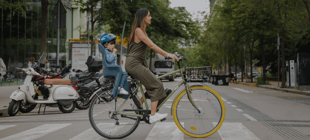 A mother cycling with her child in a rear bike seat on a city street, from Kleta's website hero